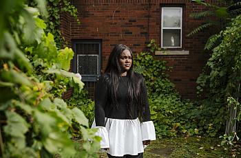A person in black and white dress standing against a tree