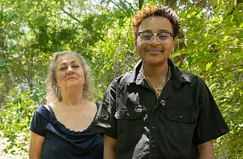 Two people standing next to each other in greenary