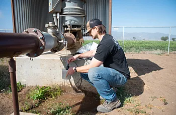 Person working on a farm and collecting water from pipe