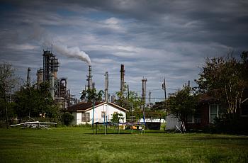 An independent house with a green grass lawn with industrial chimneys in the background