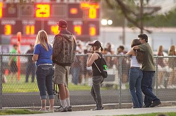 People watch a football game over a fence