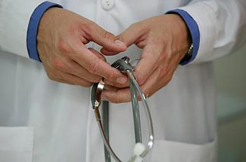 Person wearing white lab coat and holding a stethoscopes