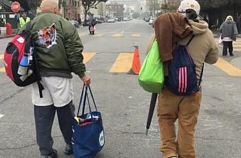 Two people walking on a street with their bags
