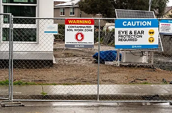 Warning signs posted on a fence at a construction site.