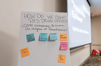 Board with multiple stickies with text written on them with a projector screen in the background