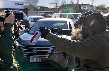 A person brandishing a spray upon journalists