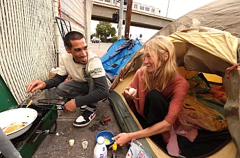 Two people preparing breakfast on street
