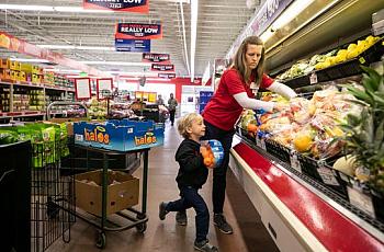 Jenny Kute and four-year-old son Henry put out fresh produce at the family's Save-A-Lot on Taylor Boulevard in the Hazelwood nei