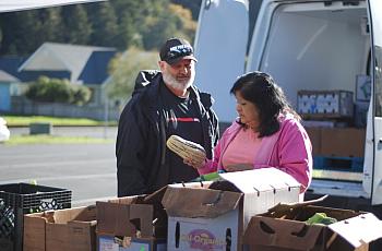 Shayne Britt and Roxie Reyes examine a delicata squash at an October visit of Food For People's Mobile Produce Pantry to Klamath
