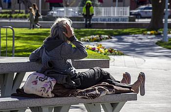 A homeless woman rests on a bench at Todos Santos Plaza in Concord, Calif., on Feb. 15, 2022.