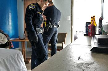 Bakersfield police officers scour a motel room where they found a small amount of methamphetamine on a dresser.