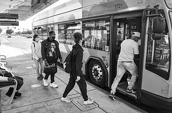 Passengers board a bus at a stop near Manchester Center in Fresno. 
