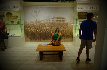 A Sicangu Youth Council member looks at a historic photograph of children forced to attend Carlisle Indian Residential School ov