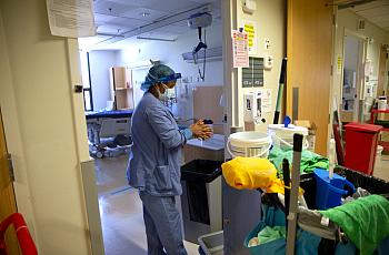 A member of housecleaning services disinfects her hands after cleaning a room in a COVID-19 unit at a Seattle hospital last year
