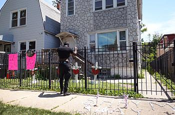 Friends, family and neighbors stop to view crosses placed in the front yard of a home after a shooting in June 2021 in Chicago, 