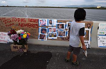 Un niño observa las fotos de mujeres víctimas de feminicidios que se colocaron como homenaje en el puente Teodoro Moscoso