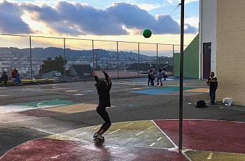 A Carver Elementary School student plays tetherball on the schoolyard at sunset with a staffer from the after-school program.