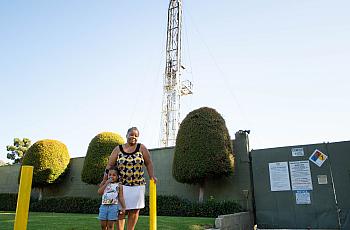 Deborah Bell-Holt and her granddaughter stand before an oil drilling site just blocks from her South Los Angeles home.