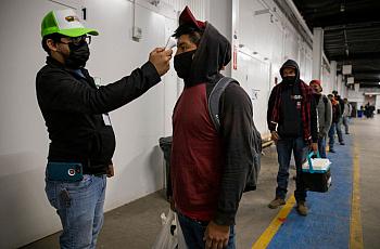 Migrant farm laborers have their temperature checked before boarding a bus to their shift in King City, California in April 2020