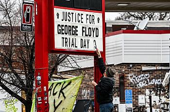 A man changes the number of a sign board at a makeshift memorial of George Floyd before the third day of jury selection begins i