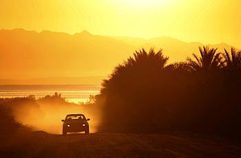 A car drives down a dusty road near the Salton Sea.