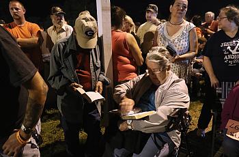 People read the bible while waiting to get free health care services at a mobile clinic in Wise, Virginia. (Photo by John Moore/