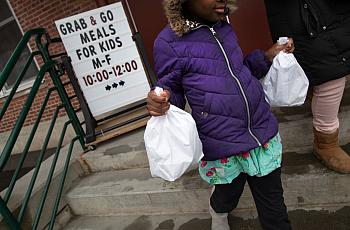 A student carries home bagged meals given out as part of a grab-and-go meal program run by public schools in Stamford, Connectic