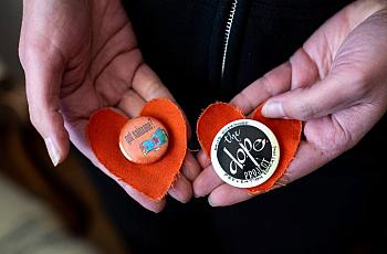 Rachel McLean holds two pins on orange fabric hearts from the memorial for Pete Morse, at her home on March 10, 2022.
