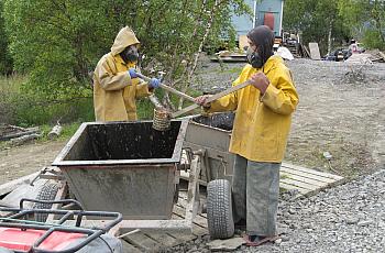 A 2011 photo shows residents of Pitkas Point, Alaska wearing breathing apparatus transfer human waste to a collection bucket, wh