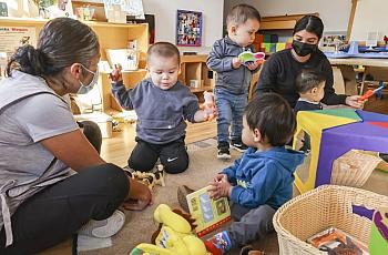 Teachers Lucy Arevalo (left) and Karina Palomino (right) play with children at Miren Algorri’s family child care.