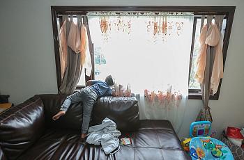 Jace Jarrett, 4, stands on his family’s large couch and peers out the window waiting for his father to come home from work on a 