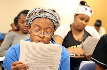 Cailah Porter, 15, reads over an example of a short story as she and fellow Upward Bound students prepare to work in groups to c