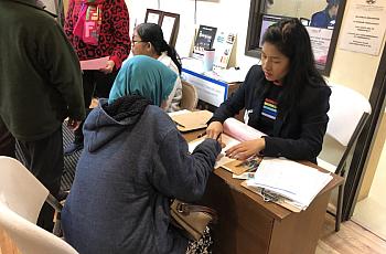 A health program director at the Cambodian Family, helps a client fill out paperwork. Many community organizations help bridge t