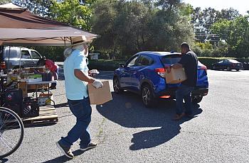 Volunteers help load boxes of food into vehicles after asking drivers how many boxes of food they want on June 4, 2021.