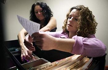 Rachelle Autry, left, and Crystal Copley sort through client files in The Healing Place women's center office. Copley started in detox at The Healing Place in January 2011, and now helps others there