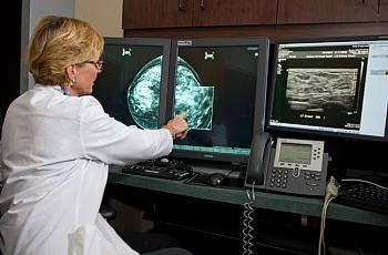 Doctor examines digital mammogram, pointing to a possible cancer. Credit: National Cancer Institute