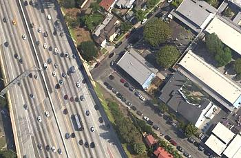 Students line up outside El Marino Language School as vehicles zoom by on Interstate 405 in Culver City, California.