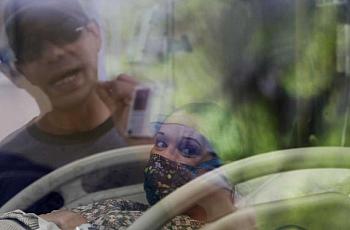 Alex Benavidez, 35, talks with his wife, Kayla, 31, through the window of a maternity room at Uvalde Memorial Hospital