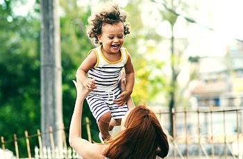 woman holding toddler girl up in the air