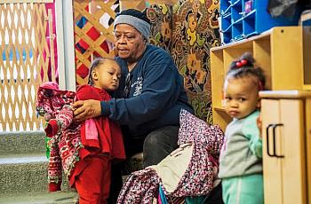 Evelyn West, great grandmother of Kee'Mayah West, 2nd grader, of North Braddock, Pa., dresses children at Great Start Day Care i