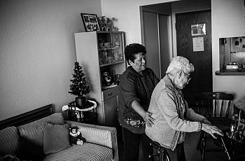 Maria Martínez helps her client, Agripina Castellanos, as she walks inside her Angelus Plaza apartment. (Photo by Bear Guerra)