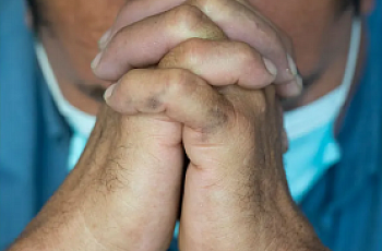 Man folds hands to pray