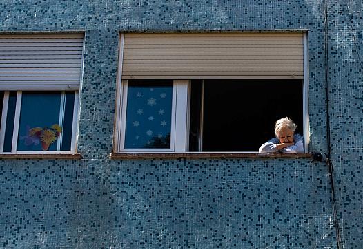 Old woman staring of the her apartment's window