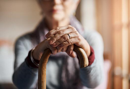 Old woman sitting while holding her cane