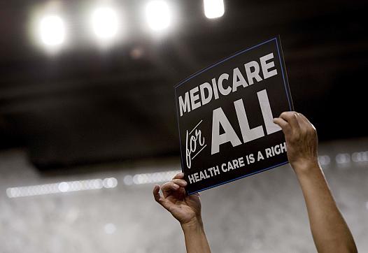 person holding up a banner for Medicare for all