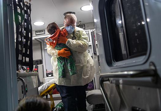 Medical worker placing a kid in the ambulance