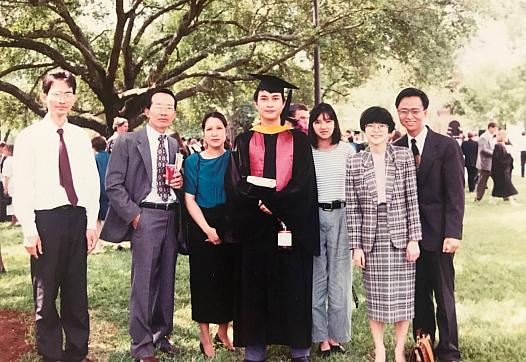 Group of people, one of whom is in a graduation cap and gown