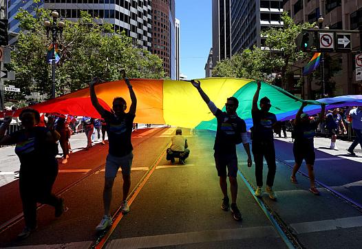 Marchers carry a pride flag down the street.