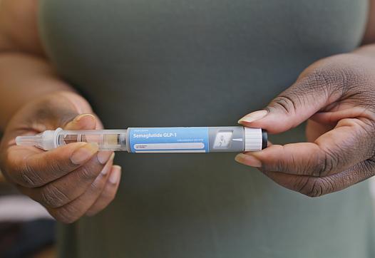 Photo of a Black woman holding GLP-1 medication.