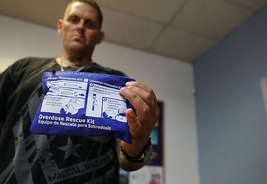 Image of an healthcare worker showing Nasal Naloxone kit in camera 